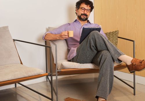 Hombre adulto relajado leyendo y tomando una taza en un ambiente sereno para el artículo sobre gestión de la ansiedad y regulación del sistema nervioso en Laguna de Duero